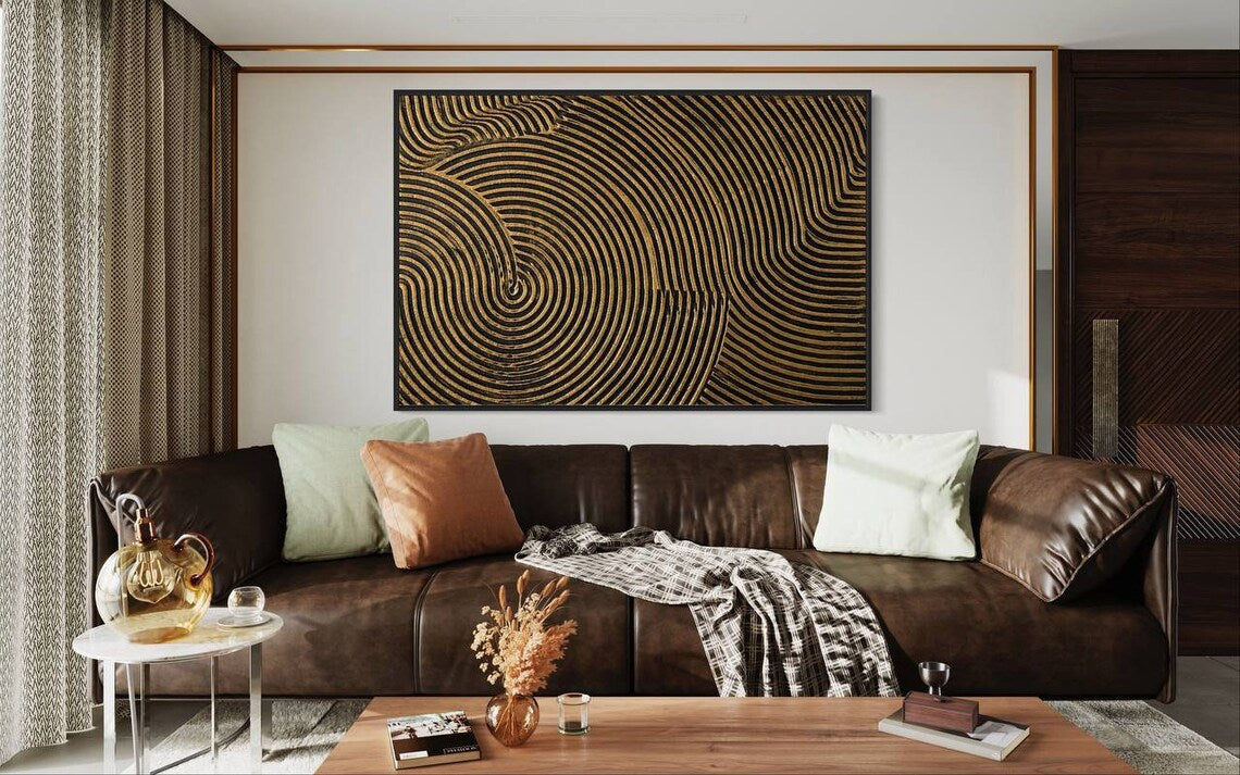 Metallic abstract canvas painting with gold and black concentric circular patterns.